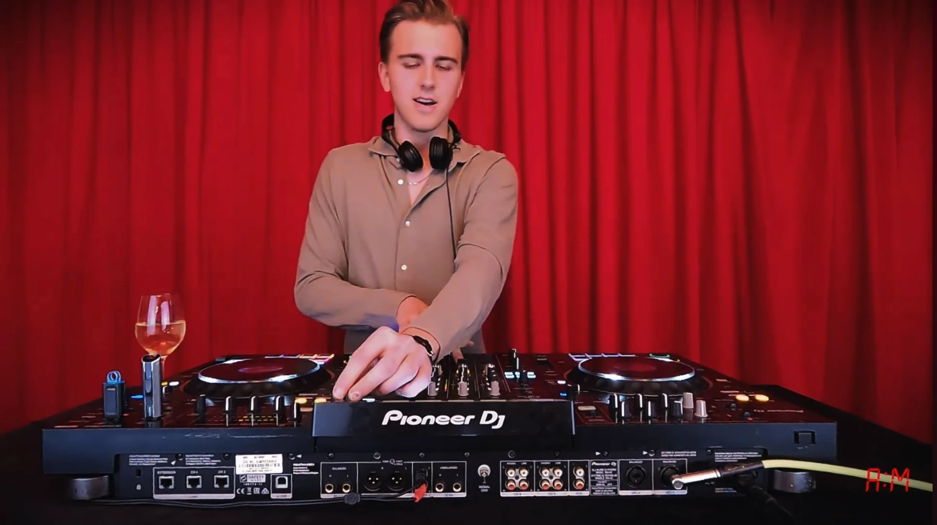 Oscar Stenberg bakom en Pioneer DJ-bänk framför röd ridå